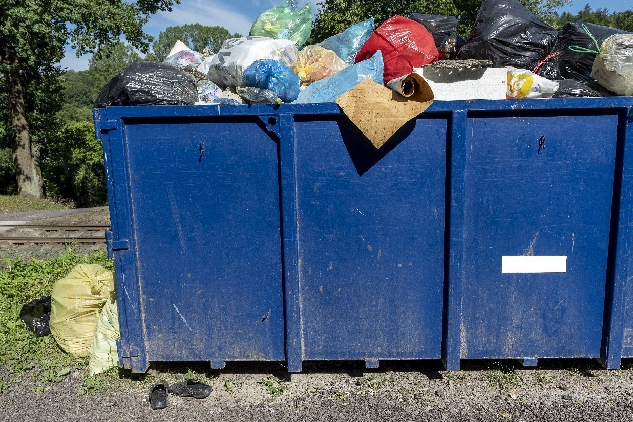 blue large mixed waste container next to a rail