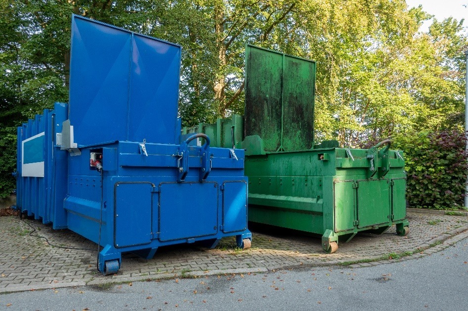two garbage compactors standing next to each other