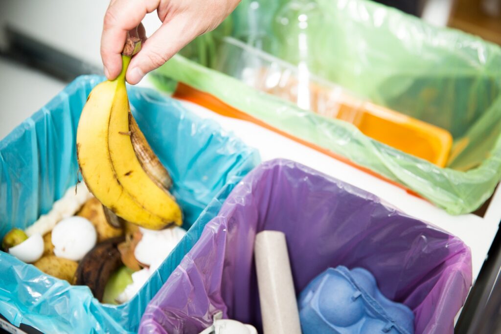 Woman putting banana peel in recycling bio bin in the kitchen