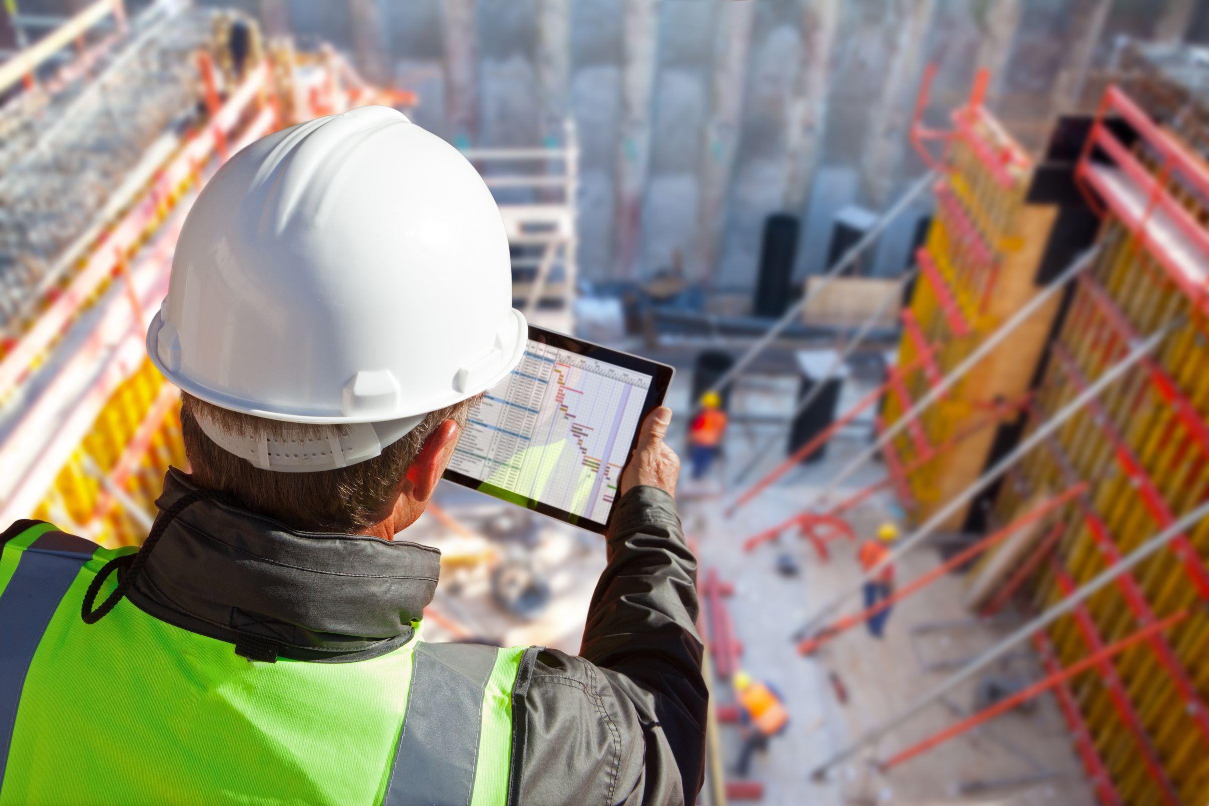 civil engineer or architect on construction site checking schedule on tablet computer