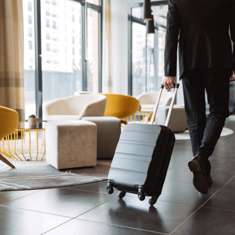 businessman wearing suit walking with suitcase in hotel lobby