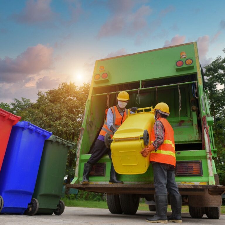 Two garbagemen emptying dustbins for trash removal with truck loading waste and trash bin.