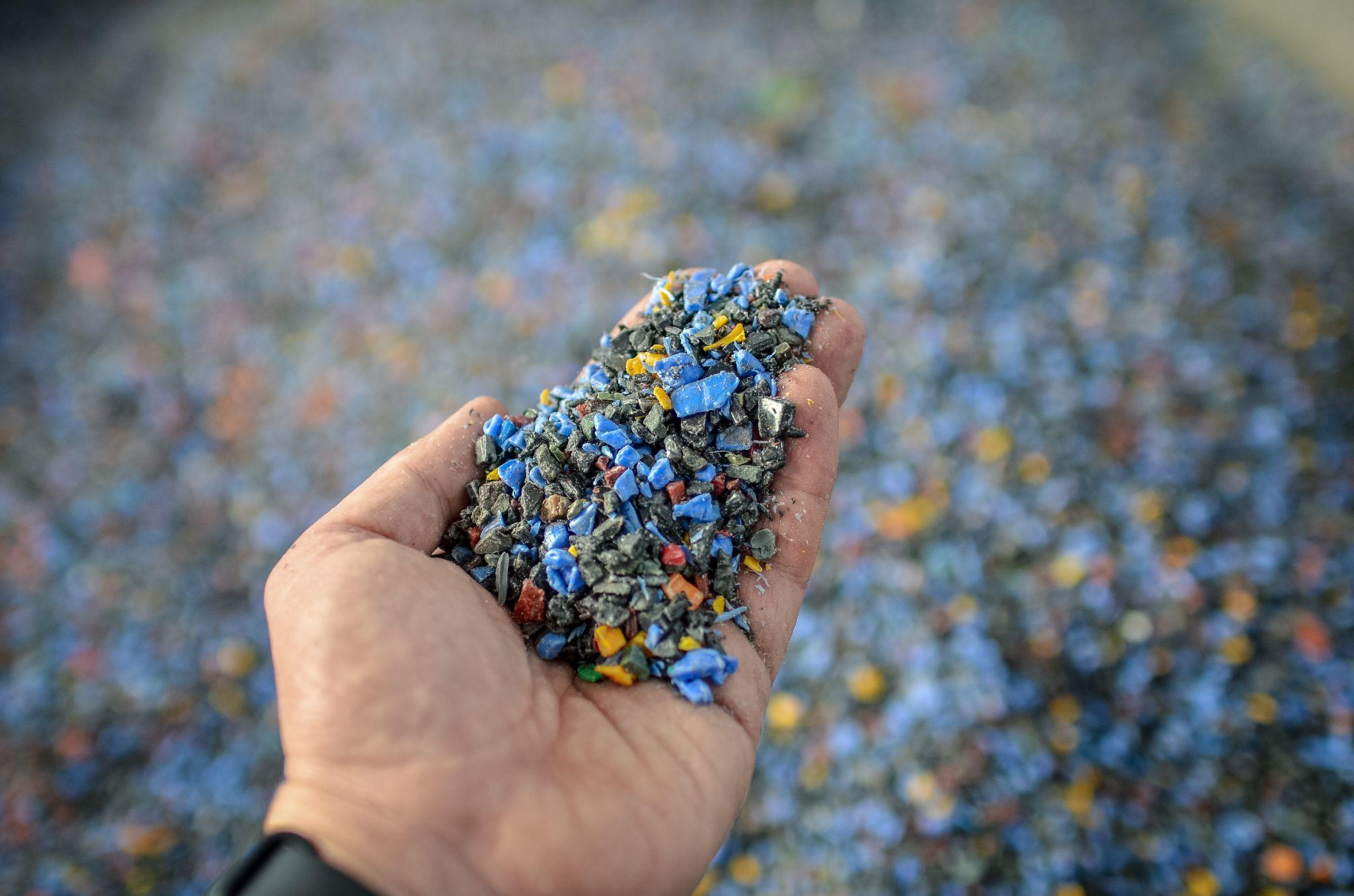 Hand holding recycled plastic chips as raw material in production.