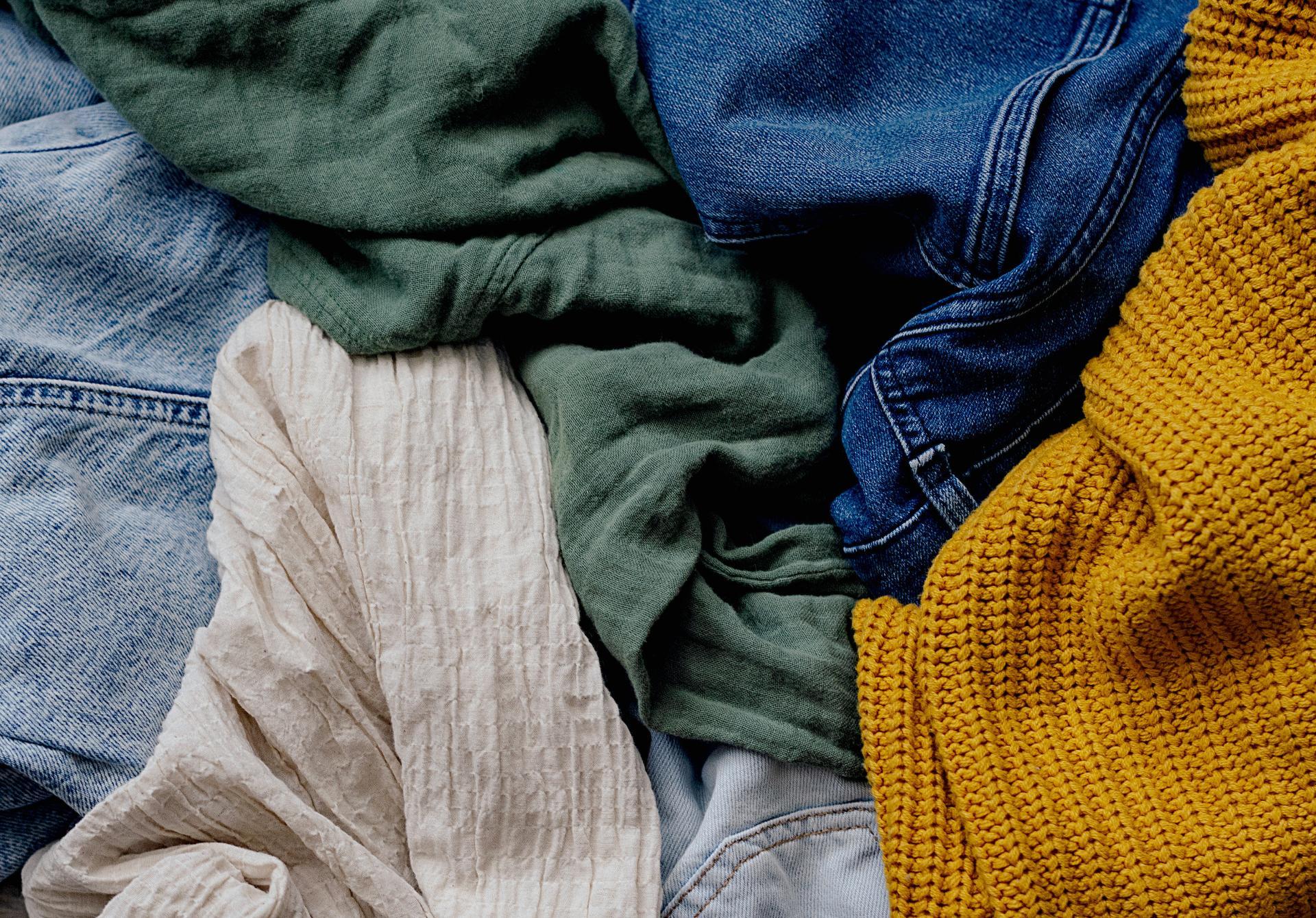 An assortment of clothing textures in various colors: green fabric, blue denim, mustard knit, and beige crinkle.